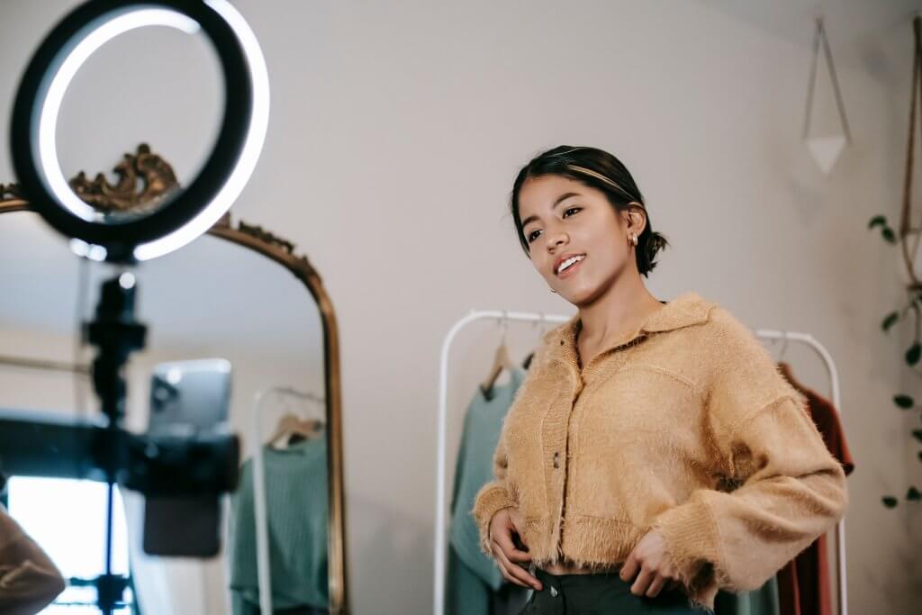 Content creator filming a video on her smartphone with a ring light, promoting products on TikTok Shop for Amazon sellers